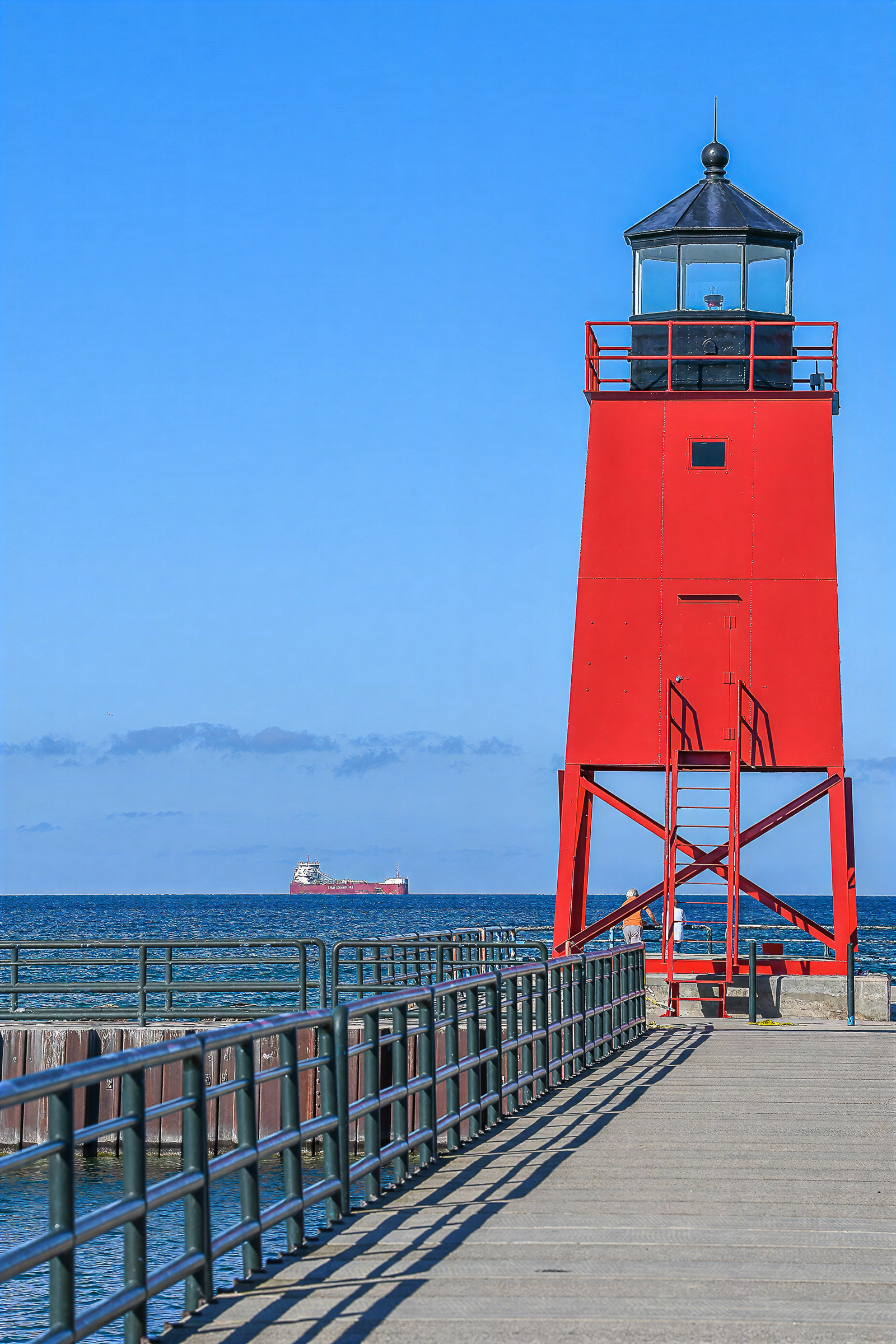 Charlevoix lighthouse with a Great Lakes freighter passing in the distance